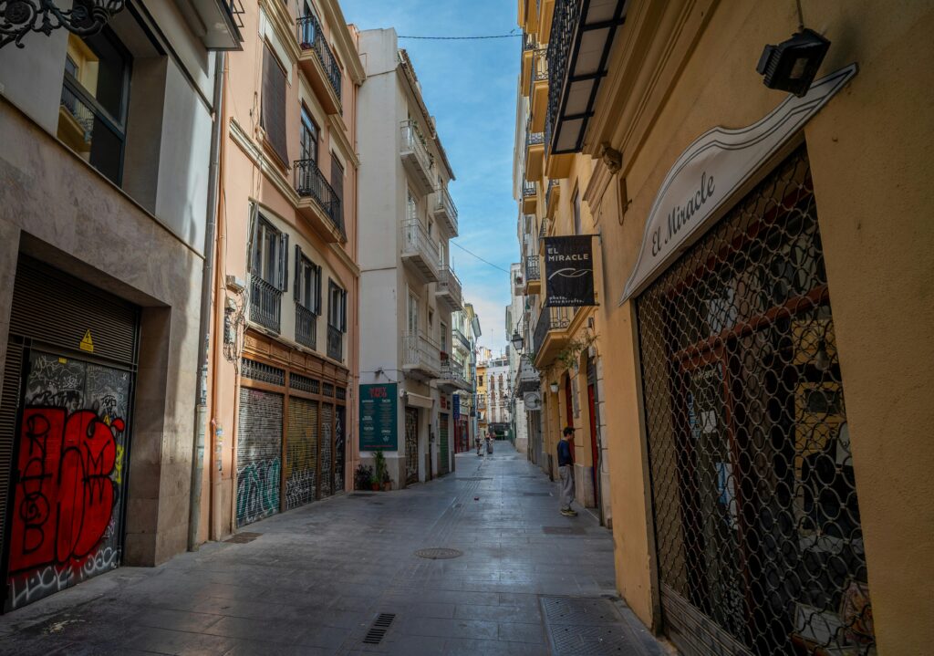 Explore a quaint alleyway in Valencia's historic quarter, revealing its urban charm and vibrant street art.